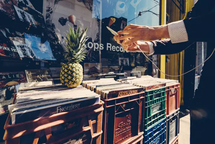 A person taking pictures of record crates with their mobile phone.